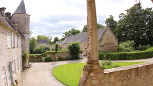 Un bâtiment historique en pierre, doté d’une tourelle, d’une allée sinueuse et d’une pelouse bien entretenue.