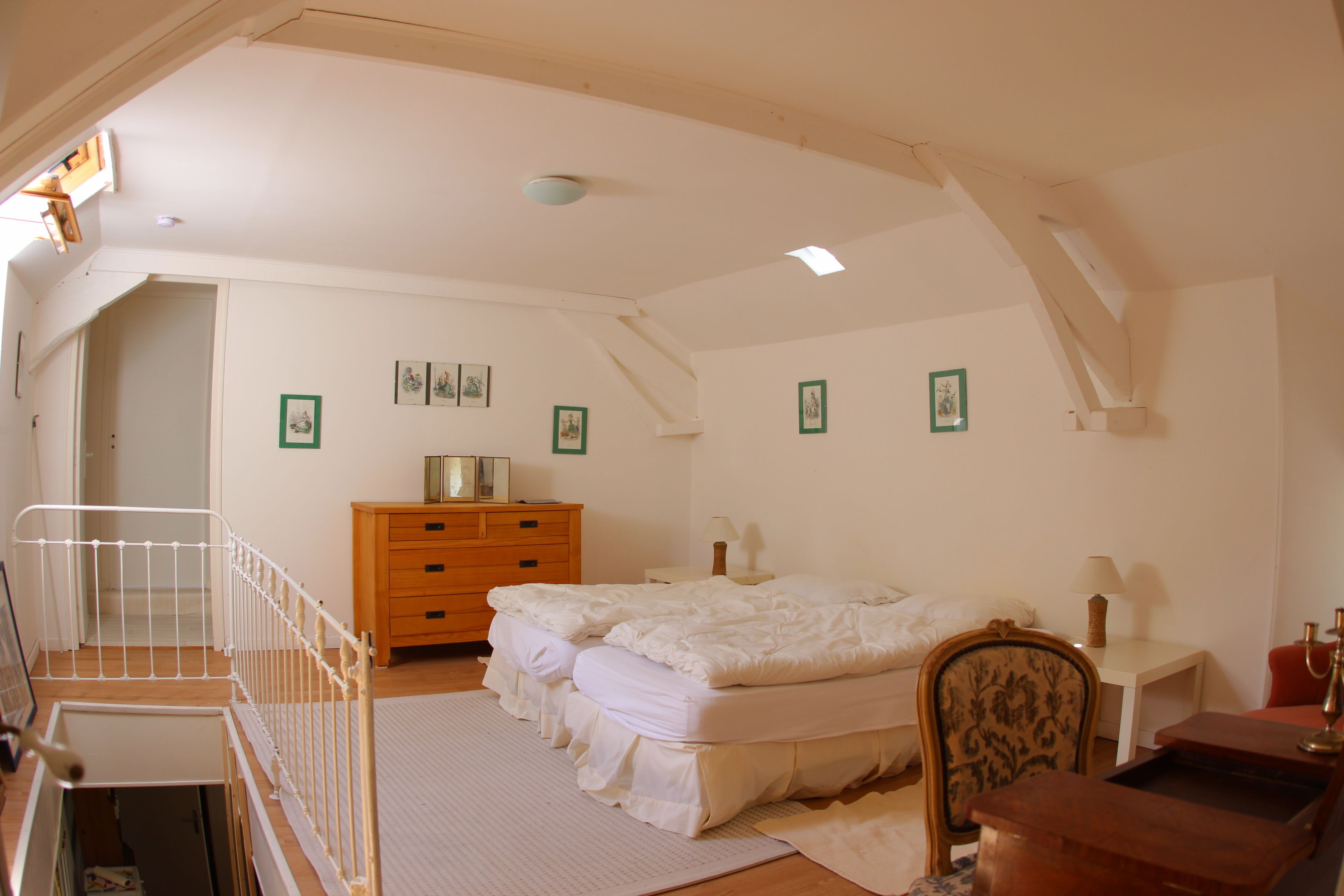 Een slaapkamer met een bed, een dressoir, een nachtkastje en een kleine tafel met een lamp.