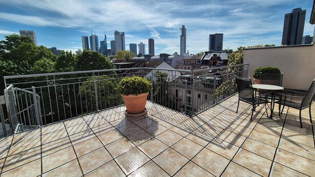 A rooftop terrace with a tiled floor, a potted plant, and a table with chairs. - Hotel Beethoven (Frankfurt)