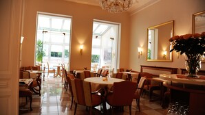 A dining area with round tables, chairs, and a chandelier. - Hotel Beethoven (Frankfurt)