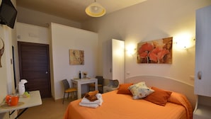 A hotel room with a bed, a desk, a chair, a table, and a door. - Agrisicilia (Castelvetrano)
