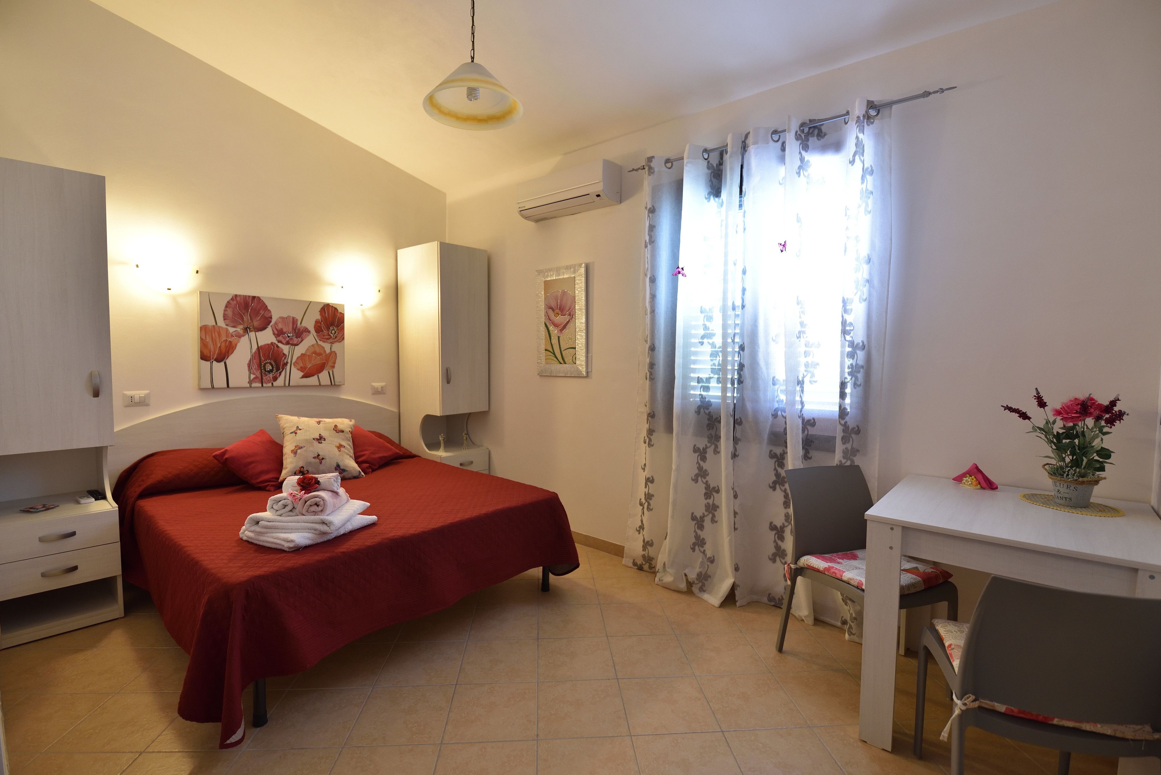 A bedroom with a bed, bedside tables, a desk, and chairs.