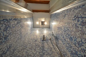 Un bagno con piastrelle a mosaico blu, una doccia e un lampadario a soffitto.