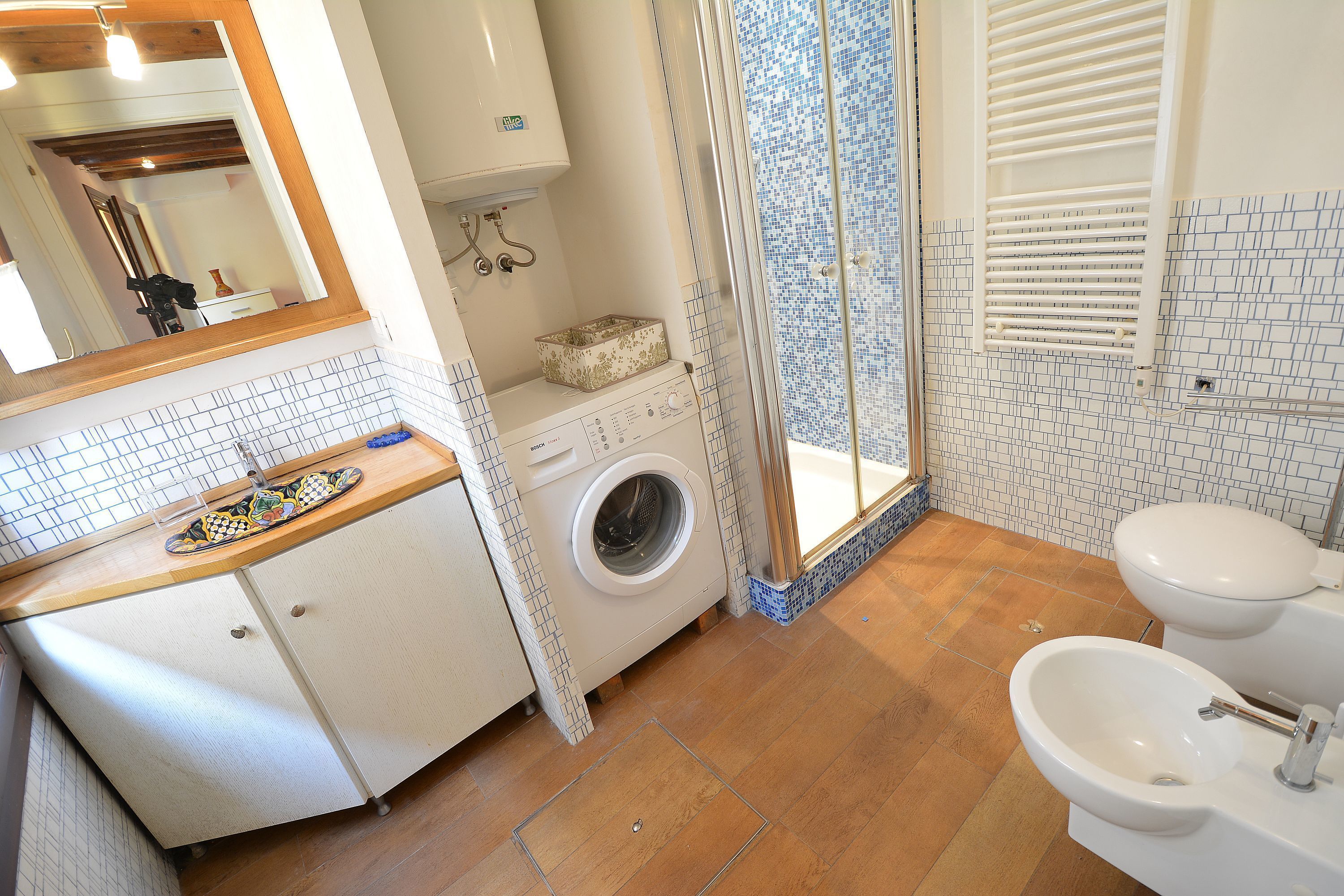 A bathroom with a washing machine, a sink, and a toilet.