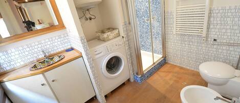 A bathroom with a washing machine, a sink, and a toilet.
