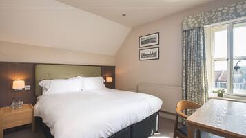 Ein Hotelzimmer mit einem großen Bett, einem Nachttisch mit Lampe, einem Sessel und einem Fenster mit Vorhängen.
