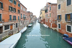 Un canal estrecho en un distrito histórico veneciano, con barcos amarrados a ambos lados.