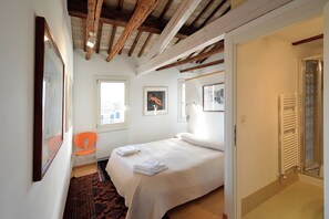 A bedroom with a bed, a chair, a radiator, and a window. - DANDOLO-Terrace (Venice)