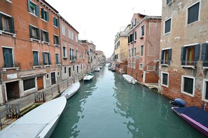 A narrow canal flanked by historic buildings with balconies and windows, boats docked along the sides. - DANDOLO-Terrace (Venice)