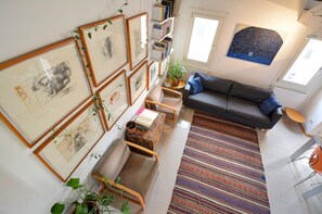 Uma sala de estar com sofá, cadeiras, mesa de centro e tapete estampado.
