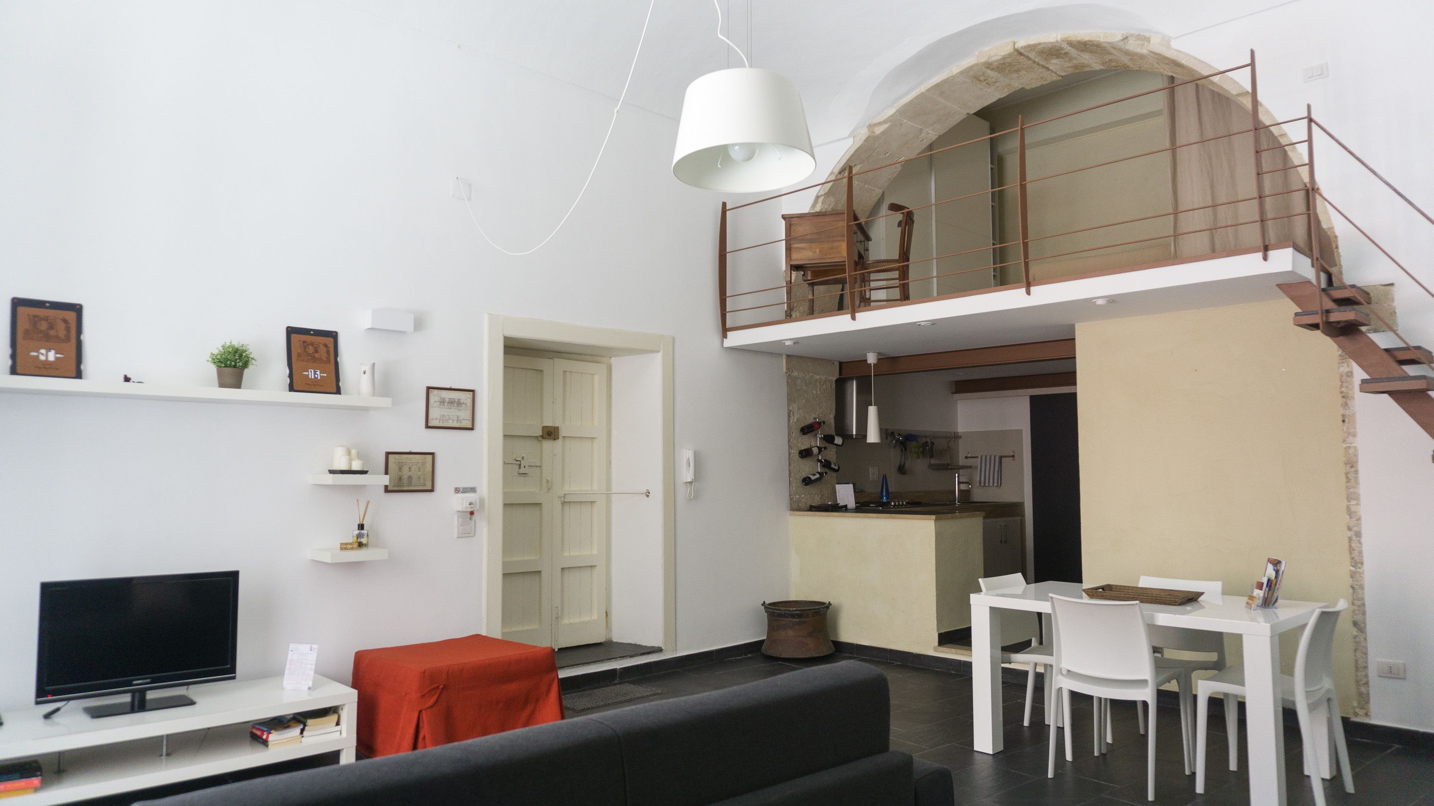 Un appartement moderne comprenant un salon, un coin repas, une cuisine et une chambre en mezzanine.