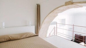 A bedroom with a bed, a window with curtains, and a view of an outdoor area. - 1743 Loft Siracusa (Syracuse)