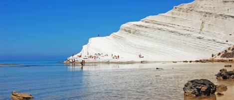 A beach with white cliffs and clear blue water.