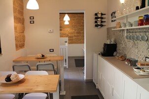 Una cocina moderna con una mesa de madera, sillas y una encimera con diversos utensilios de cocina.