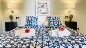 A hotel room with a large bed, two nightstands, a painting on the wall, and two wall lamps. - B&B Donna Teresa (Agrigento)