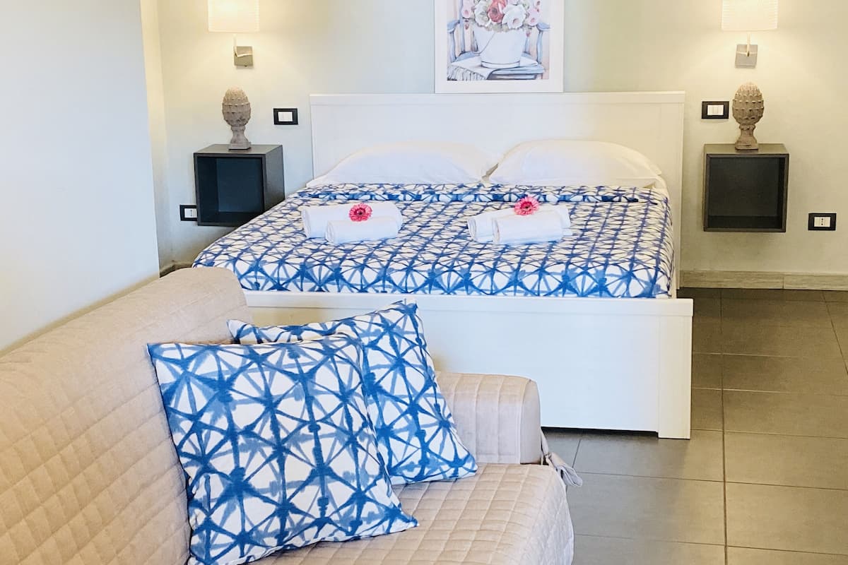 Una habitación de hotel con una cama, un sofá y dos mesitas de noche con lámparas.
