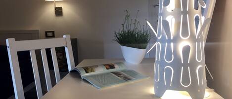 A table with a magazine, a potted plant, and a modern lamp.
