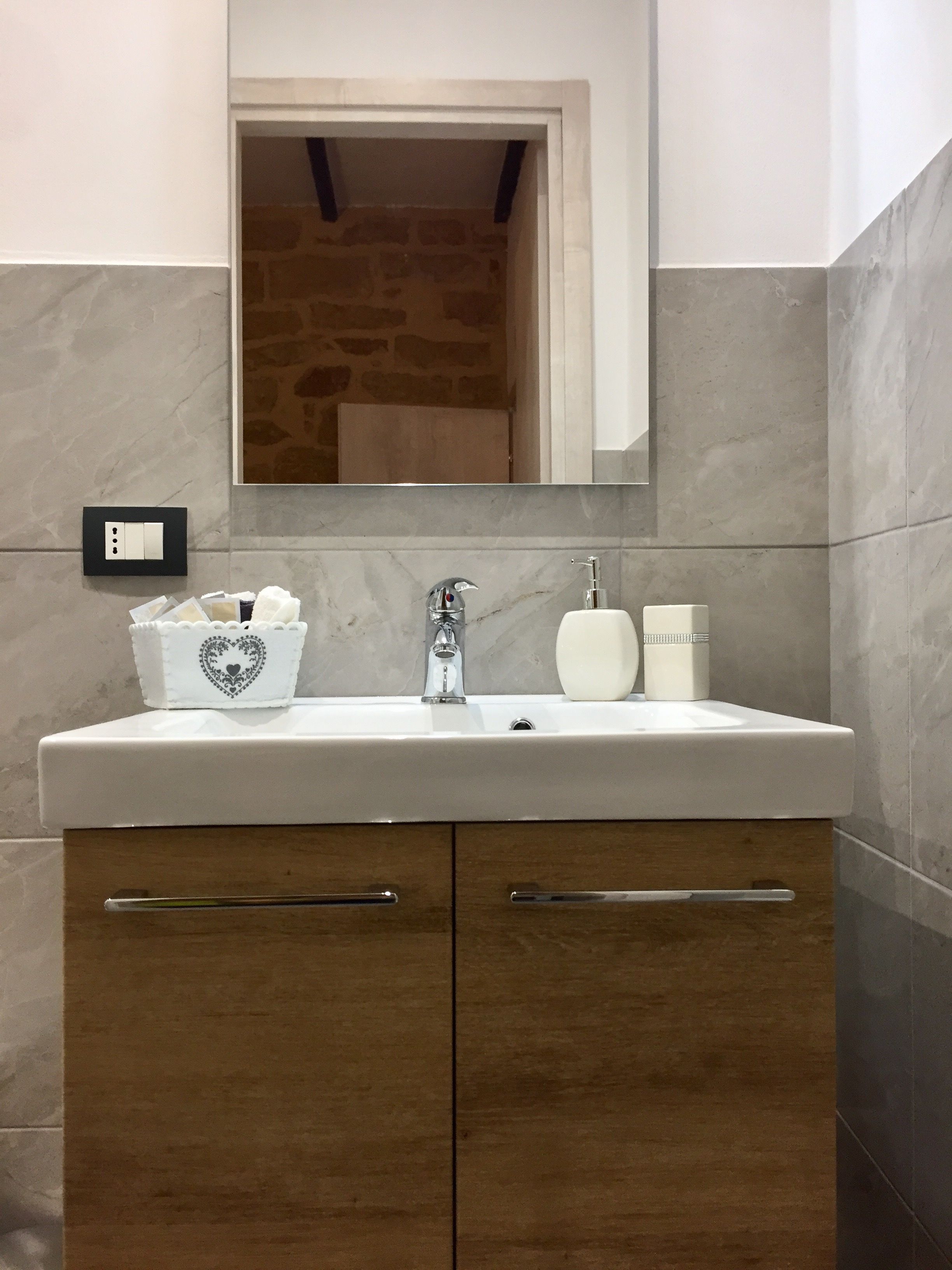 A bathroom with a white sink, a mirror above it, and a wooden cabinet below.