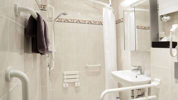 A modern bathroom with a shower, toilet, and sink, equipped with grab bars and a hand dryer.