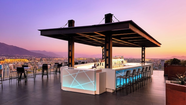 Un bar en la azotea con diseño moderno, que incluye una barra y una zona de estar.