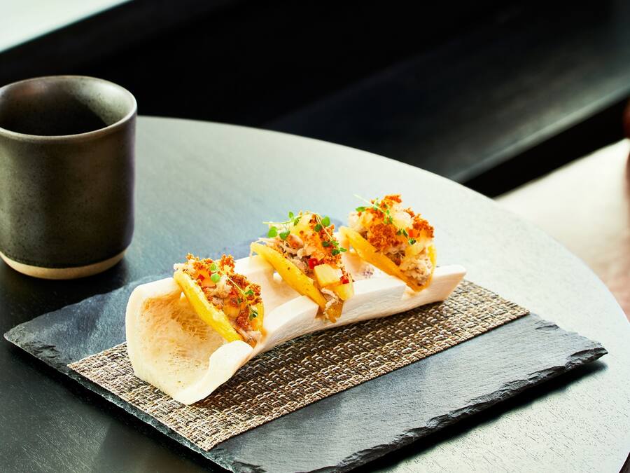 A dessert plate with a dessert on a slate serving board, accompanied by a dark cup.
