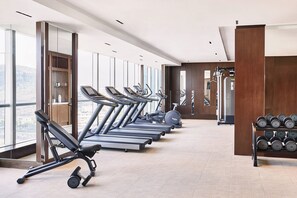 Un gimnasio con cintas de correr, mancuernas y equipo de ejercicio.