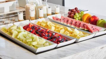 Un bufé con diversas frutas y postres.