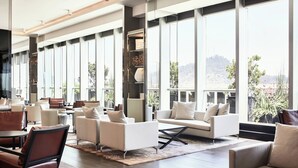 Un salón amplio con diversas opciones de asientos, ventanas grandes que ofrecen vistas al exterior y un diseño interior moderno.