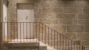 A stone staircase with a metal railing leading to a white door. - Casa do Outeiro (Povoa de Lanhoso)