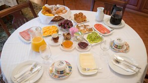 A breakfast table with various food items, drinks, and utensils. - Casa do Outeiro (Povoa de Lanhoso)