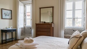 A hotel room with a bed, a dresser, a mirror, and a window with a view. - Casa do Outeiro (Povoa de Lanhoso)