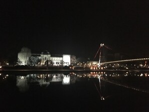 A nighttime view of a cityscape with a bridge and buildings reflected in a body of water. - KNM MS Switzerland II - Frankfurt (Frankfurt)