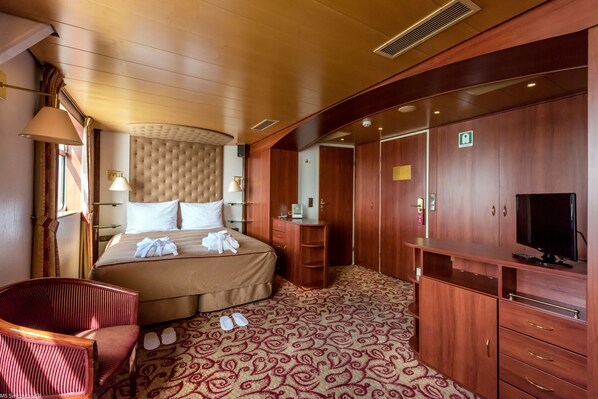 A hotel room with a bed, a wooden wardrobe, a television, and a patterned carpet. - KNM MS Switzerland II - Frankfurt (Frankfurt)