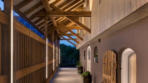A covered corridor with wooden beams, potted plants, and arched doorways.