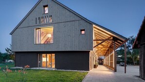 A modern barn-style building with large windows and an open interior space.
