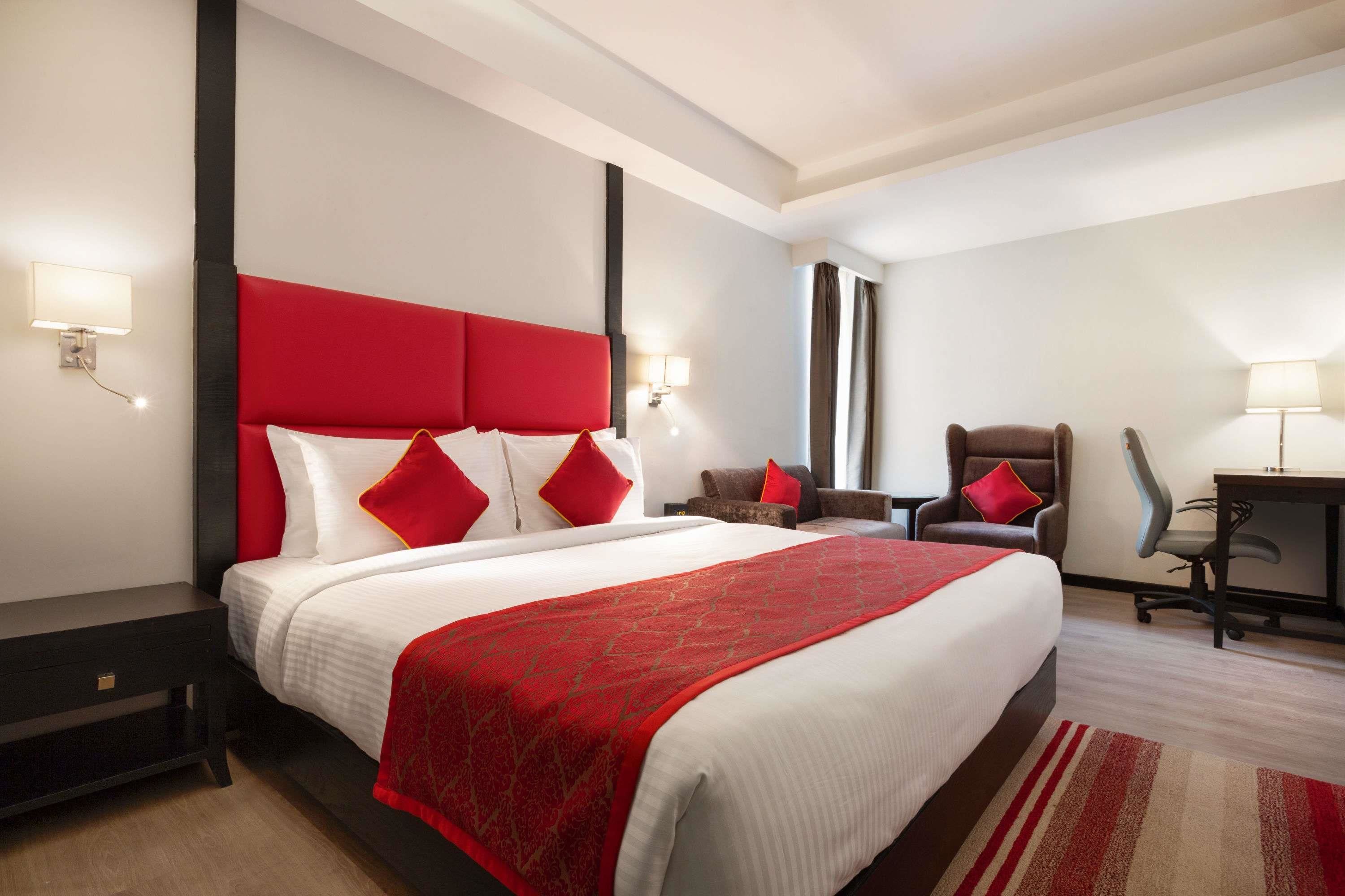 A hotel room with a large bed, a desk, a chair, and a small table.