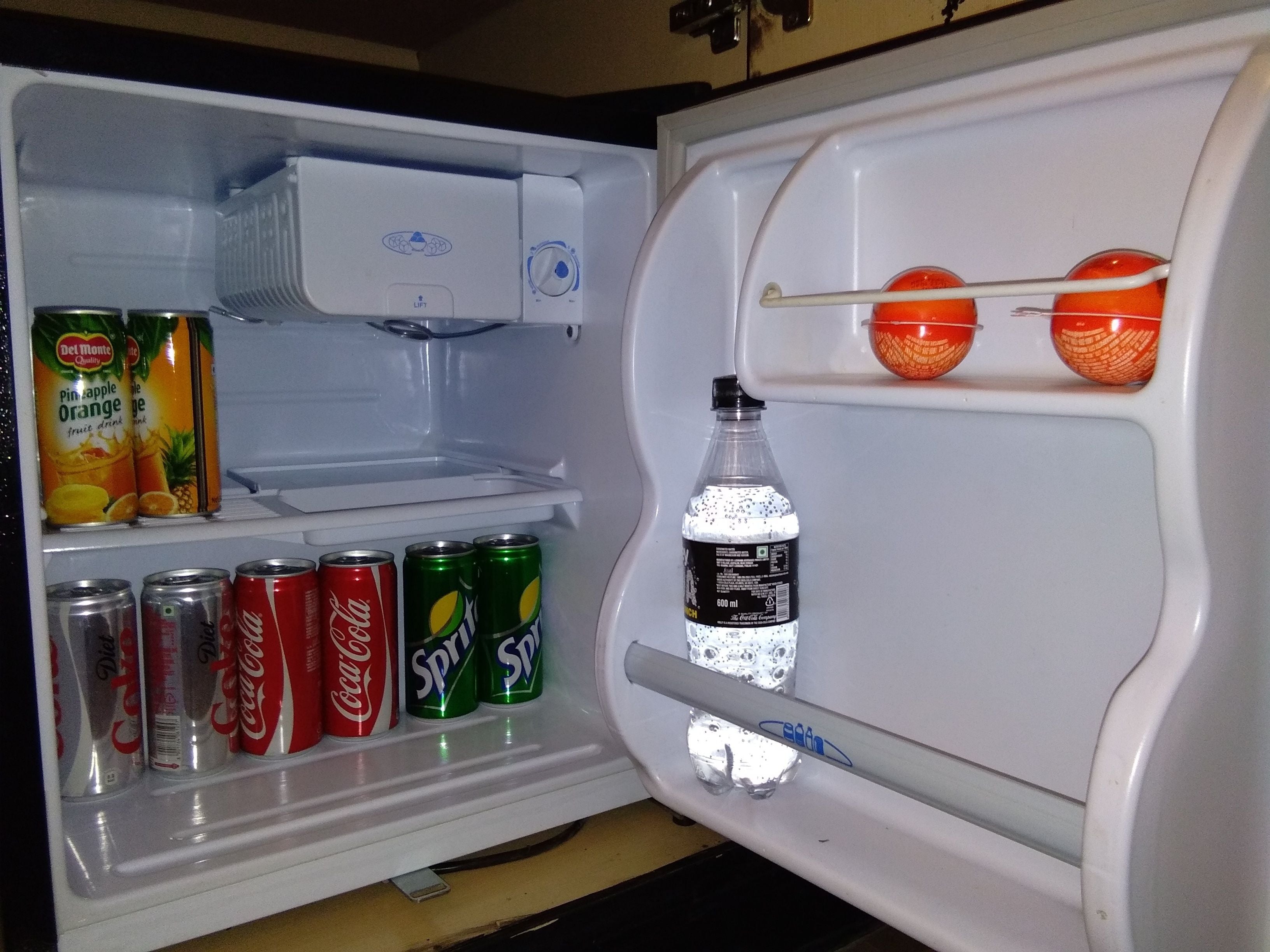 Refrigerador obert amb prestatges que contenen diverses begudes i una ampolla d'aigua.