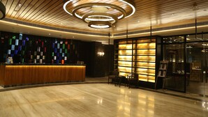 A modern hotel lobby with a wooden reception desk, a colorful wall, and a circular light fixture. - Ramada Encore by Wyndham Jalandhar (Jalandhar)