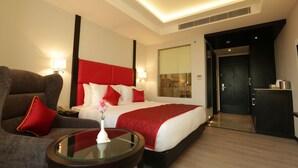 A hotel room with a bed, a sofa, a glass table, and a nightstand. - Ramada Encore by Wyndham Jalandhar (Jalandhar)