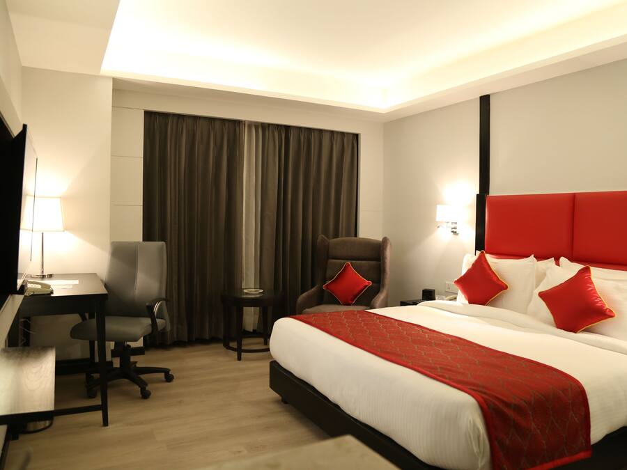 A hotel room with a large bed, a desk, a chair, and a small table.