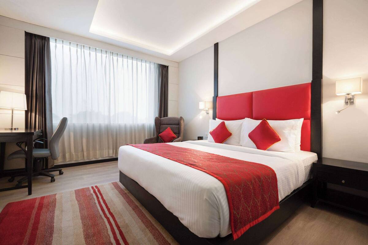 A hotel room with a large bed, a desk, and a chair.