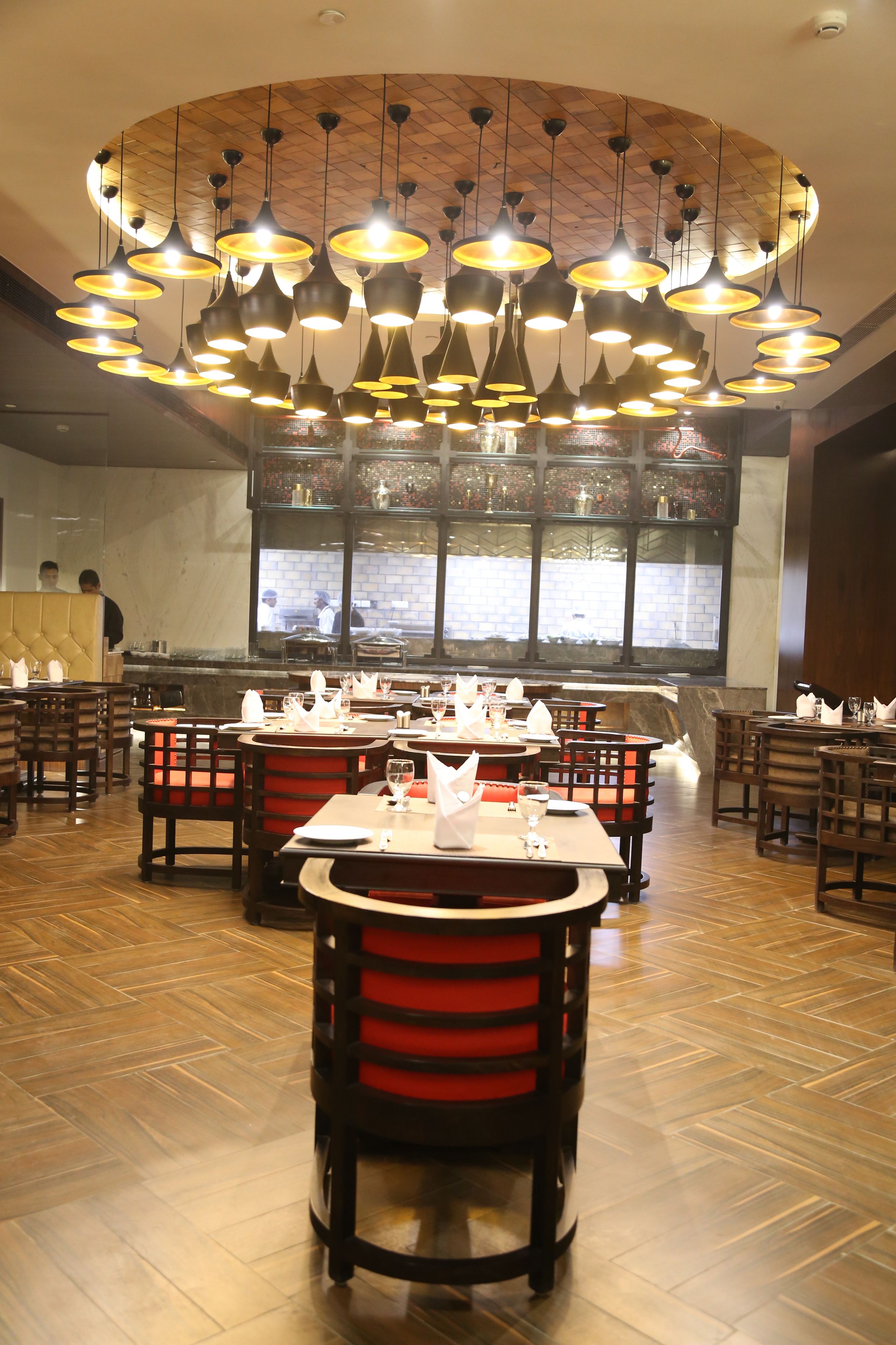 A restaurant interior with multiple dining tables and chairs, a central island, and a large window with a view of the street.