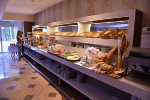 A buffet setup with various food items and a person serving.