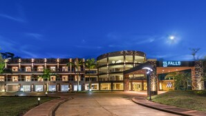 A multi-story hotel with a curved glass facade, outdoor lighting, and a sign reading "FALLS".