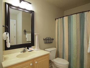 A bathroom with a sink, mirror, toilet, and a shower curtain. - Beach Bucket GC1006 (Port Aransas)