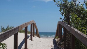 A wooden pathway leading to a beach with a clear view of the ocean.