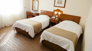 A hotel room with two beds, a wooden headboard, a bedside table with a lamp, a mirror, and a framed picture on the wall. - Hotel Polanco (Mexico City)