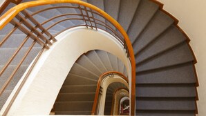 A spiral staircase with a wooden handrail and carpeted steps. - Hotel Polanco (Mexico City)
