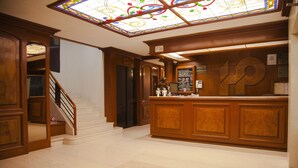 A reception area with a wooden reception desk, a staircase, and a stained glass ceiling. - Hotel Polanco (Mexico City)