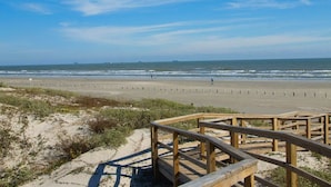 Une plage avec des promenades en bois menant à la rive, des dunes de sable et l’océan.